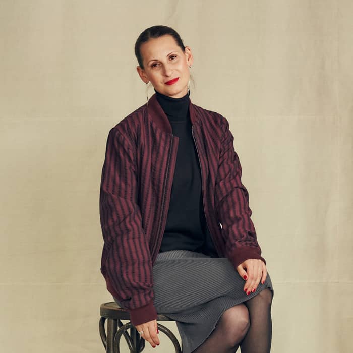 Eine Frau in einem Blouson auf einem Hocker